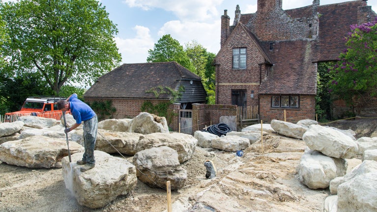 A worker jetwashes a large piece of stone, during work to recreate the Delos Garden at Sissinghurst Castle Garden, Kent